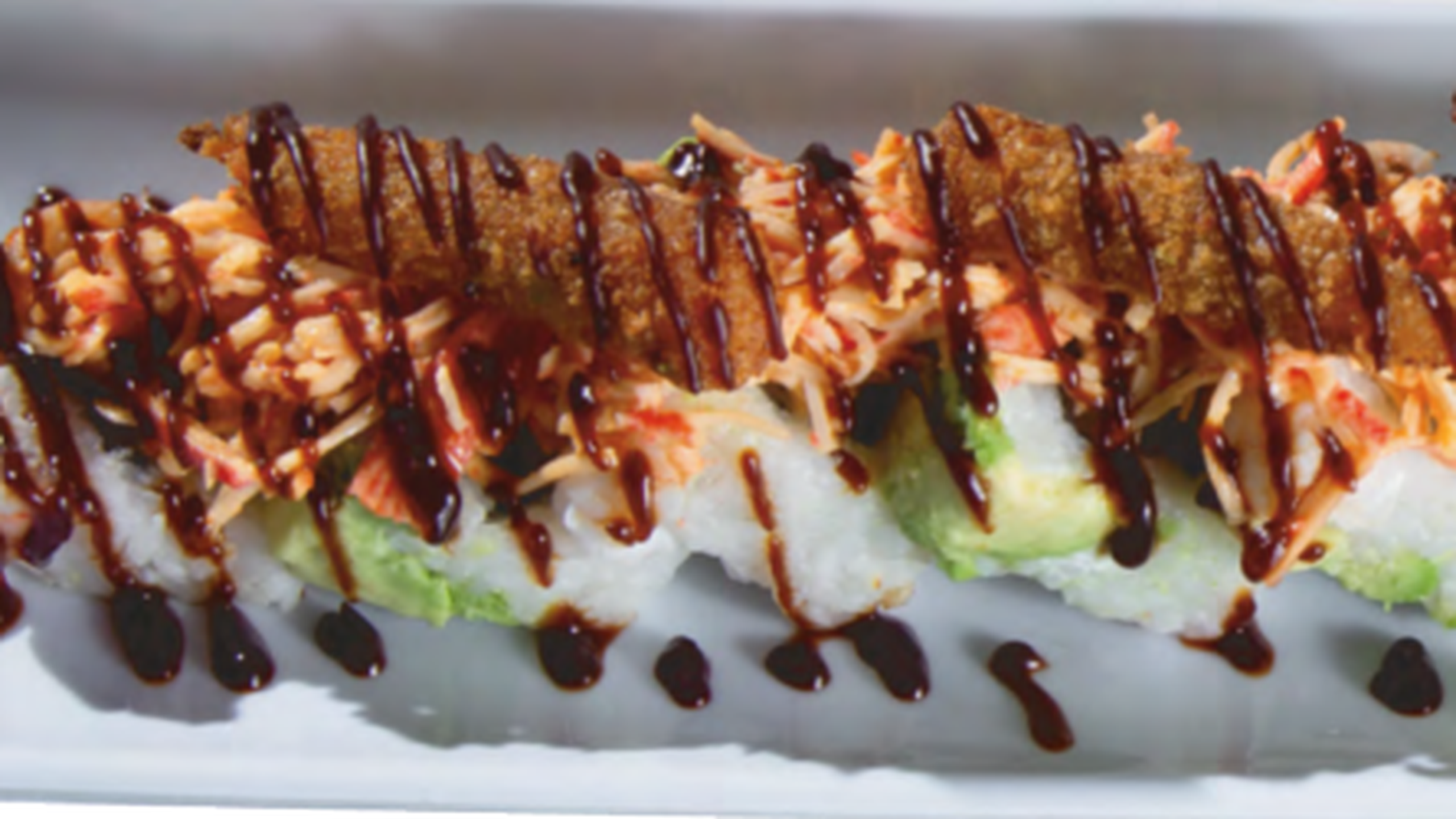 Rollo de sushi empanizado con aguacate, surimi y salsa